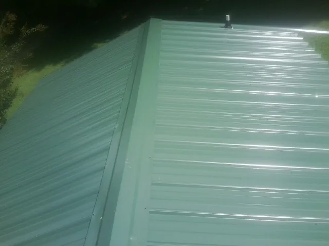 New green metal panels meeting at the ridge of a roof — Flat Roof Repair work by our crew in Decker