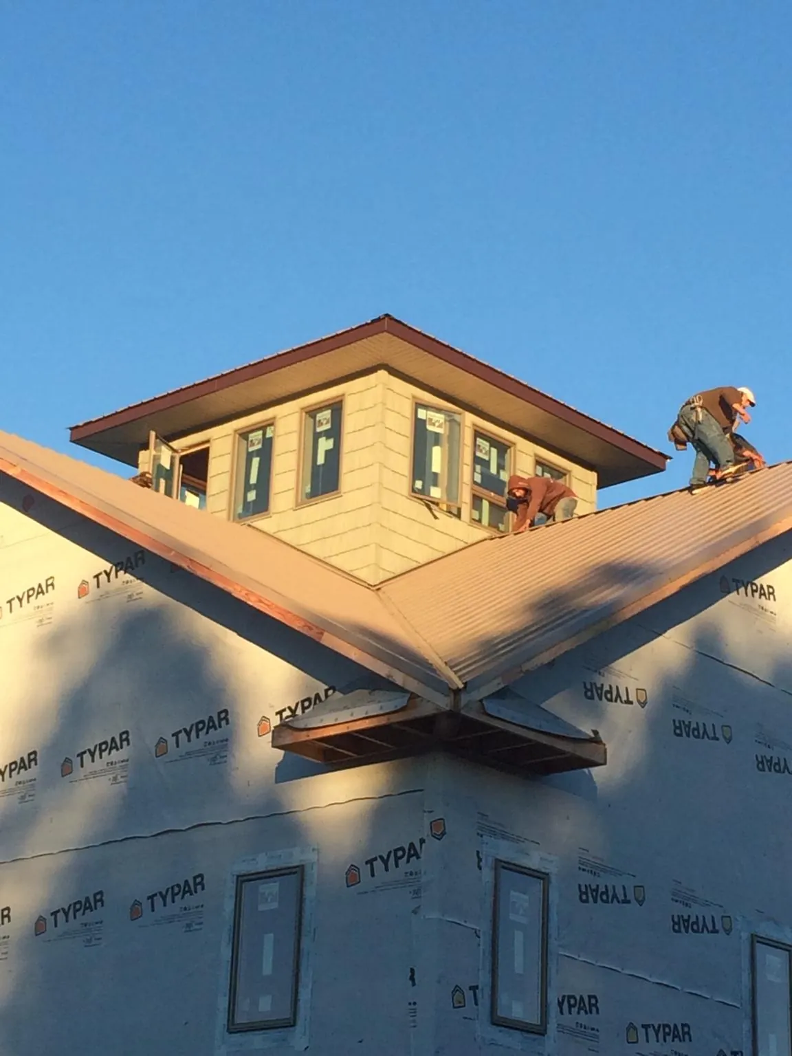 Roofers working around a rooftop cupola on a new metal roof at sunset — Roof Waterproofing in Decker by Roofing Brothers